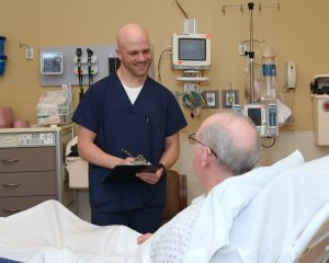 At TriHealth Bethesda Butler Hospital near Cincinnati, Ohio, nursing student Derek Anderson interviews a patient to uncover unmet social needs that might impede his recovery. Photo: Shane Gamble